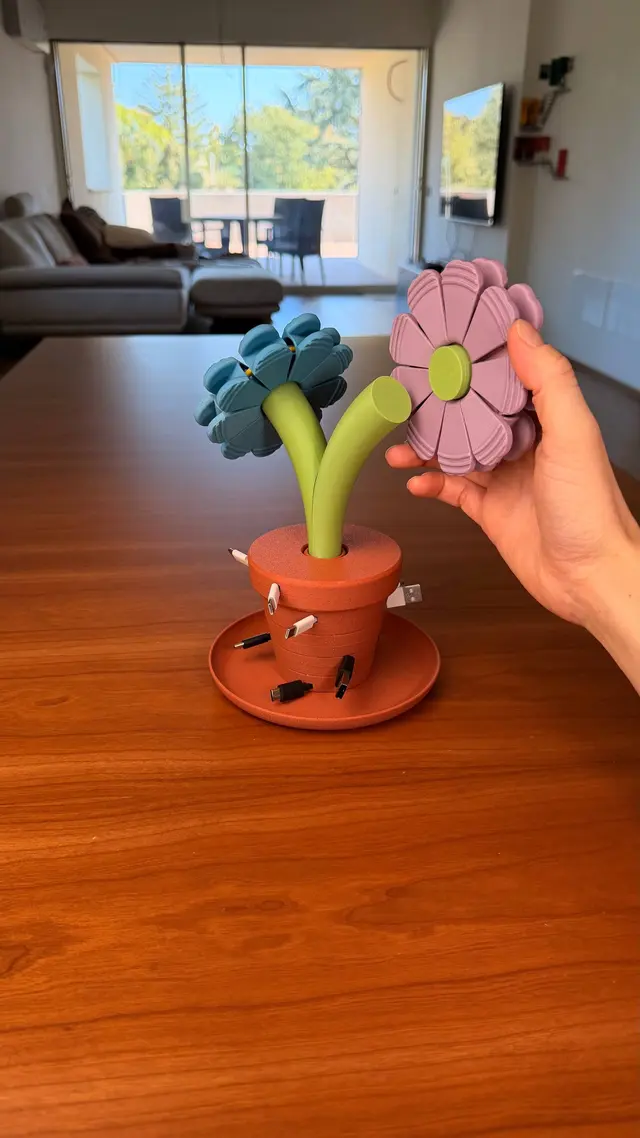 Una mano solleva un fiore rosa vicino al vaso Bloom Stack, con un fiore azzurro accanto