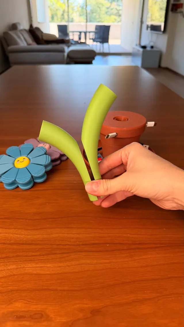 Un gambo e un fiore azzurro tenuti in mano accanto al vaso
