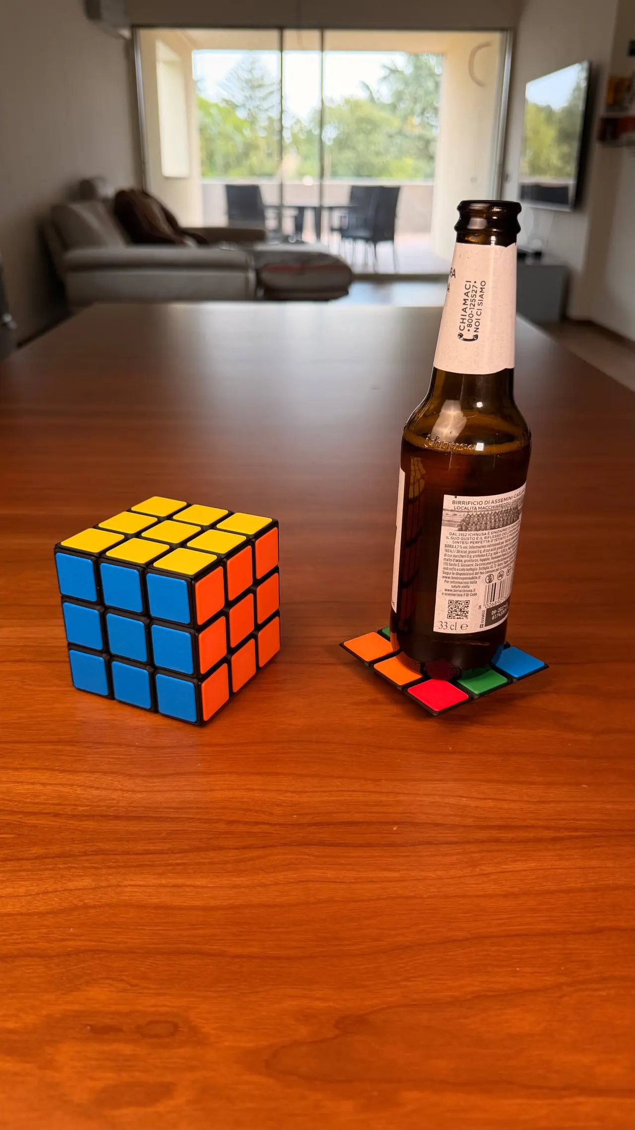 Il cubo, un sottobicchiere e una bottiglia sul tavolo