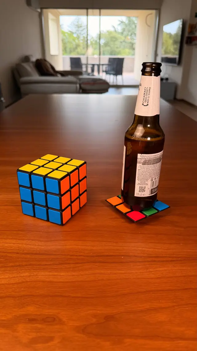 Il cubo, un sottobicchiere e una bottiglia sul tavolo