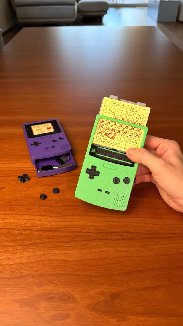 La Memo Boy verde con i pulsanti staccati e una console viola sullo sfondo